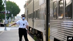 2022 年 9 月 15 日，在伊利诺伊州阿灵顿高地的梅特拉阿灵顿高地站，一名客运火车列车员发出放行信号。（美联社照片）