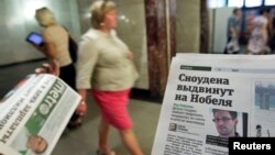 Một người phát báo cho khách bộ hành, trong thủ đô Moscow, Nga, có đăng tin về Edward Snowden trên một trang của tờ báo, 2/7/13