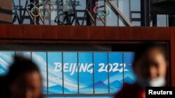 戴着口罩的行人在新一波冠状病毒病 (COVID-19) 爆发后出现在在2022 年冬奥会和冬残奥会北京组委会办公大楼附近。(路透社照片)