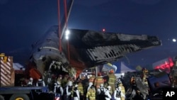 2024年12月29日,救援人员在韩国务安国际机场飞机起火现场抬着一名乘客的遗体。