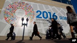 有人在国际货币基金组织总部外面走过(2016年4月14日)。墙上有各国国旗图案。