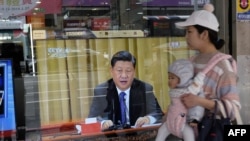 2019年1月2日,台湾新北市,一位母亲带着孩子经过一台电视,上面显示中国领导人习近平就台湾问题发表讲话。
