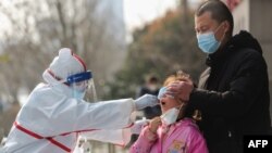 中国武汉的医务人员在给一个女孩进行核酸检测。(2020年3月5日)