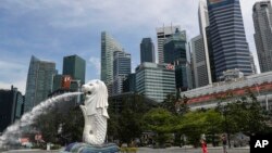 在新加坡滨海湾地区,人们在鱼尾狮雕像前拍照留念,与金融天际线相映成趣。(资料照片,2020年6月30日)
