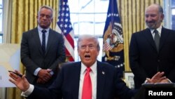 美国总统特朗普在白宫签署行政命令,卫生与公众服务部部长肯尼迪与商务部长卢特尼克站在两旁。(2025年2月25日)