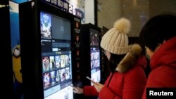 人们在天津一家影院的自动售票机前印电影票。(资料照)