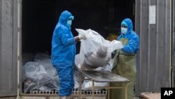 资料图: 斯里兰卡的卫生部门工作人员正在处理疫情死者的遗体。(美联社2021年8月11日)