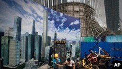 资料照:建筑工人在北京中央商业区的一处建筑工地围墙外休息。(2018年6月26日)