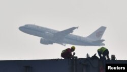 四川成都展览中心建筑工地上空飞过的中国国航飞机。(2020年2月26日)