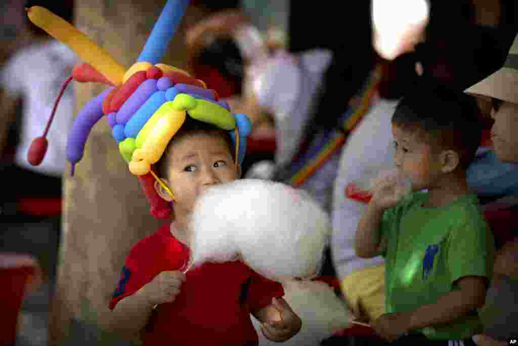 2017年6月1日，在北京的一个公园里，一名男孩戴着气球帽子,吃棉花糖。全世界许多国家庆祝国际儿童节。