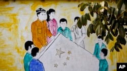 资料照片:中国西部新疆和田市团结新村一户人家的墙上的壁画,画中是维吾尔族和汉族男女举着中国国旗的场景。人权观察曾经在2024年发表报告,指中国政府一直有系统地更改维吾尔族和其他少数民族居住的村庄名称,以反映执政的共产党的意识形态。