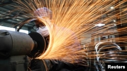 浙江杭州市一名戴着口罩的工人在生产自行车轮子钢圈的生产线上工作。(2020年3月2日)