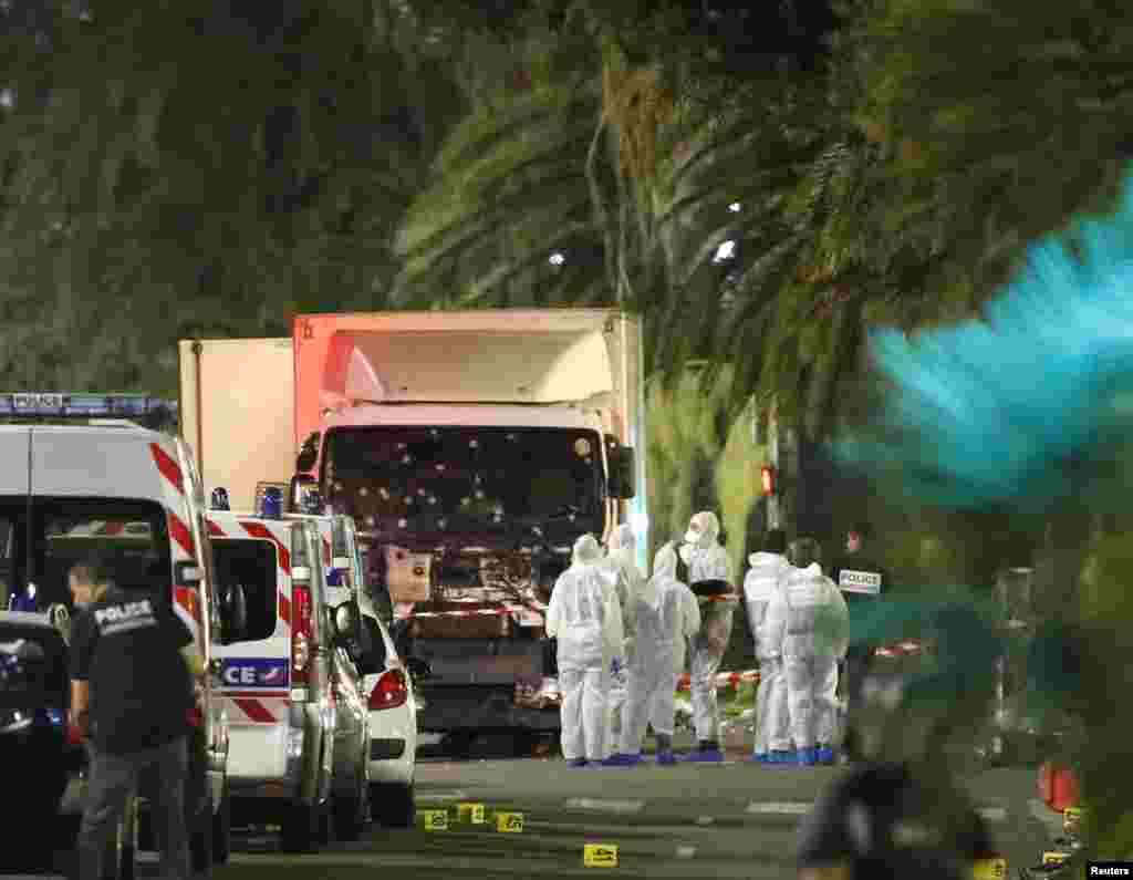 French police force and forensic officers early Friday look at the truck that ran into a crowd celebrating the Bastille Day national holiday, killing at least 77 people, in Nice, France, July 14, 2016.