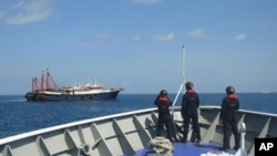 菲律宾海警队员2021年4月27日观察停靠在萨比纳浅滩的中国海上民兵船。(菲律宾海警队照片)