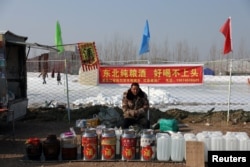 春节前北京一个露天广场内一名男子在售卖桶装白酒。(2025年1月22日)