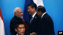 在中国东部山东省青岛举行的上海合作组织峰会上,印度总理莫迪同巴基斯坦总统侯赛因握手,中国国家主席习近平在旁边(2018年6月10日)。印度和巴基斯坦在不少方面是对头,但都是上海合作组织新成员。