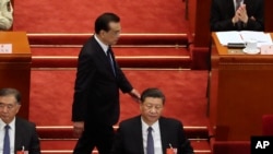 资料照:中国前总理李克强在北京人大会堂举行的全国人大年度会议开幕式期间走过中国领导人习近平的身后。(2020年5月22日)