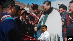 在中国西南部四川省成都市的一家酒店里,一名男子拿着雨伞走过一张中国国家主席习近平会见少数民族的照片。(2020年9月9日)