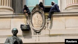 在哥伦比亚大学,一名学生抗议者从汉密尔顿楼的一座阳台把装着食物的框子吊上来。(2024年4月30日)