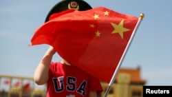 一名站在北京天安门广场的小男孩身穿美国T恤手拿中国国旗。(2019年5月7日)