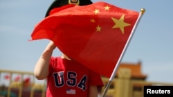 一名站在北京天安门广场的小男孩身穿美国T恤手拿中国国旗。(2019年5月7日)