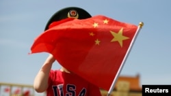 一名站在北京天安门广场的小男孩身穿美国T恤手拿中国国旗。(2019年5月7日)