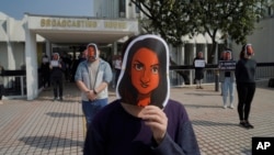 香港电台的员工头戴新闻主播利君雅的面罩在广播大楼外进行静默抗议。(2021年1月28日)