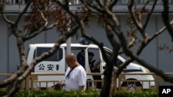 资料照:一名市民走过北京长安街一座桥下正在执勤的警车。(2024年6月4日)