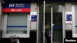 一名妇女打开上海浦东发展银行开设在北京的一所支行的大门。(2011年7月6日)