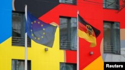 Flags of Germany, right, and the European Union flutter in the wind at the German Embassy in Kyiv, Ukraine, Jan. 24, 2022.