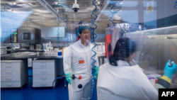 资料照:武汉病毒研究所的病毒学家石正丽(左)在该所的P4实验室内。