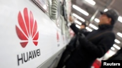 一名男子在上海的电子产品市场观看华为手机。(资料照片)