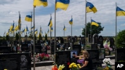 一位女士在乌克兰布查抚摸丈夫的墓碑,她的丈夫是乌克兰军人,在乌克兰顿涅茨克州阿夫卡迪伊夫卡阵亡。(2023年7月18日)