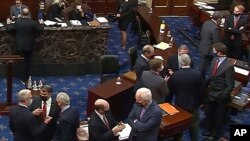 资料照片:参议院电视截屏显示共和党参议员和幕僚在针对特朗普总统的第二次弹劾审判的会场交谈。(2021年2月13日)