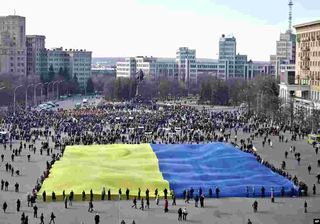 Pro-Ukrainian activists hold a huge yellow-and-blue Ukrainian flag during a rally in support of Ukraine's territorial integrity in the eastern city of Kharkiv, Ukraine, March 13, 2014.