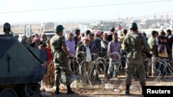 Турецькі солдати на кордоні із Сирією.За огорожею чекають сирійські курди-біженці