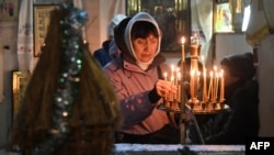 一名女子在乌克兰哈尔科夫的一座教堂里参加东正教圣诞节弥撒时点亮蜡烛。(2023年12月24日)