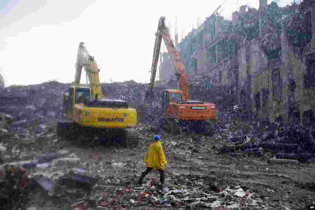 2013年5月7日,一名救援工作者冒雨走在孟加拉国萨瓦镇一座倒塌的服装厂大楼废墟中。