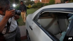 A Pakistani photographer takes photos of a bullet-riddled car belonging to journalist Hamid Mir parked at a local hospital in Karachi, Pakistan, April 19, 2014.