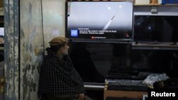 资料照片: 一名男子在一家商店内观看巴基斯坦在白沙瓦对伊朗境内的分裂主义武装分子进行了打击的新闻