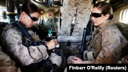 资料照片:美国海军陆战队第八团第一营的妇女接触事务队队长希娜·亚当中士(左)与医务兵珊农·克罗利坐在装甲车内准备离开她们位于阿富汗赫尔曼德省的基地,外出执行任务。(2010年11月13日)