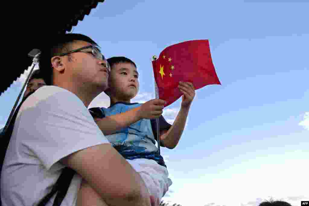 2018年9月6日,在北京的一个公园里,一名男子抱着儿子,儿子拿着国旗。 中国官方的中国社科院人口与劳动经济研究所和社会科学文献出版社1月3日发布报告,预测中国生育率为1.6。报告说,如果保持在这个水平,中国将于2027年出现人口负增长。