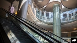 2022年5月21日,一名戴着口罩的女子在北京一家空空荡荡的商场里的自动扶梯上。