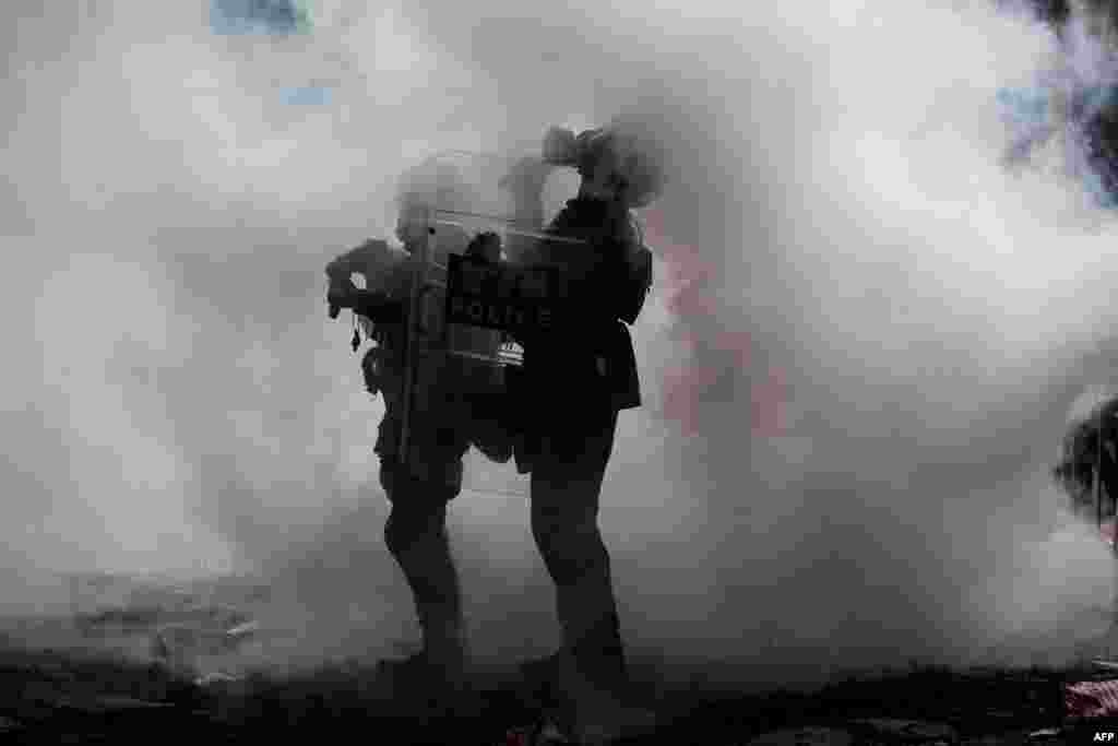 2019年6月12日,在香港政府总部外举行的反对有争议引渡法提案的集会上,警察被催泪瓦斯包围。