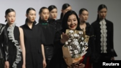 时装设计师周丽在北京举行的中国国际时装周上怀抱一把棉花做出的花束表达对新疆棉的支持。(2021年3月30日)