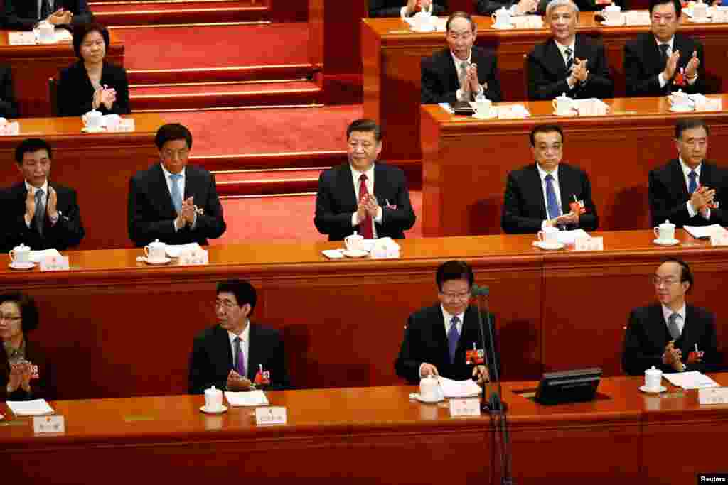 中国国家主席习近平,国务院总理李克强等官员2018年3月9日在北京人民大会堂举行的全国人民代表大会第二次全体会议上鼓掌。前排右起:马建国、 中共吉林省委书记兼省人大常委会主任巴音朝鲁、人大会议主席团常务主席之一张春贤。第三排的女代表是人大会议主席团常务主席之一沈跃跃。