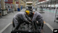 在湖北省襄阳市,腾龙汽车有限公司制造厂的工人在组装小型客车的底盘框架。(资料照片:2023年5月10日)