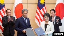 2023年12月16日,在日本东京首相官邸举行的签字仪式后,日本外相上川洋子(前右)与马来西亚外长穆罕默德·哈桑(前左)合影。(路透社)