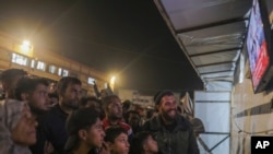 2025年1月15日,在加沙地带中部的汗尤尼斯,巴勒斯坦人在等待哈马斯和以色列宣布停火协议时观看电视广播。