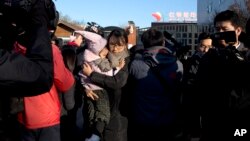 一位家长怀抱刚刚从红黄蓝幼儿园接出的孩子离开。(2017年11月24日)